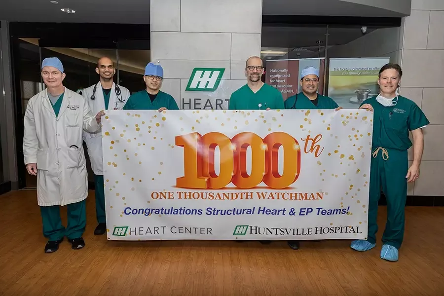 A group of Huntsville Hospital Heart Center physicians take a photo with a banner celebrating 1,000 Watchman devices implanted.